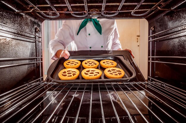 Chef-kok bereidt gebak in de oven, uitzicht vanaf de binnenkant van de oven. Koken in de oven.