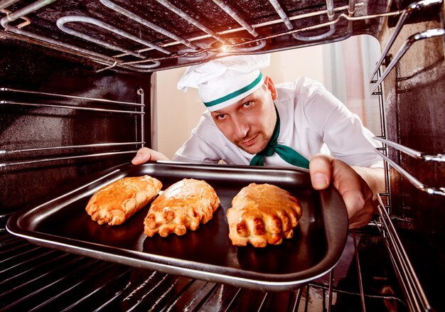 Chef-kok bereidt gebak in de oven, uitzicht vanaf de binnenkant van de oven. Koken in de oven.