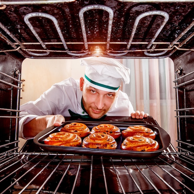 Foto chef-kok bereidt gebak in de oven, uitzicht vanaf de binnenkant van de oven. koken in de oven.