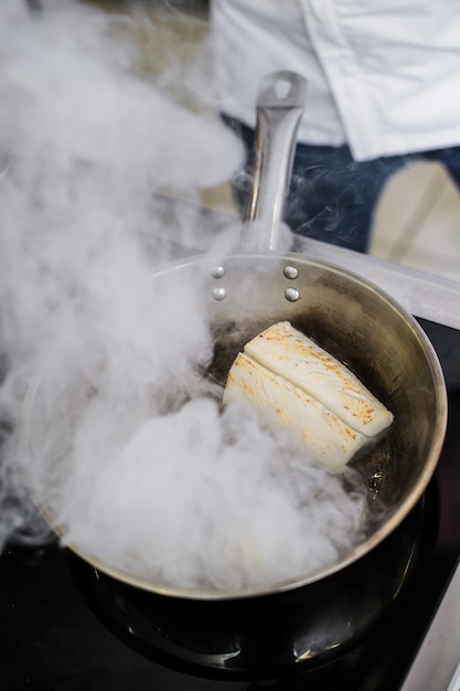 Chef-kok bereidt heilbot onder selderij in de keuken van het restaurant