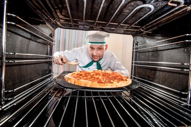 Chef-kok bereidt pizza in de oven, uitzicht vanaf de binnenkant van de oven. Koken in de oven.