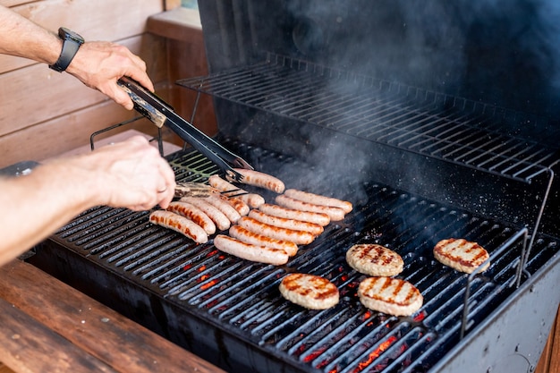 Chef-kok bereidt vlees op de grill tijdens outdoor food festival food truck brunch of catering evenement varkensvlees steaks beierse worstjes barbecue feest zomer barbecue feest of picknick in de achtertuin