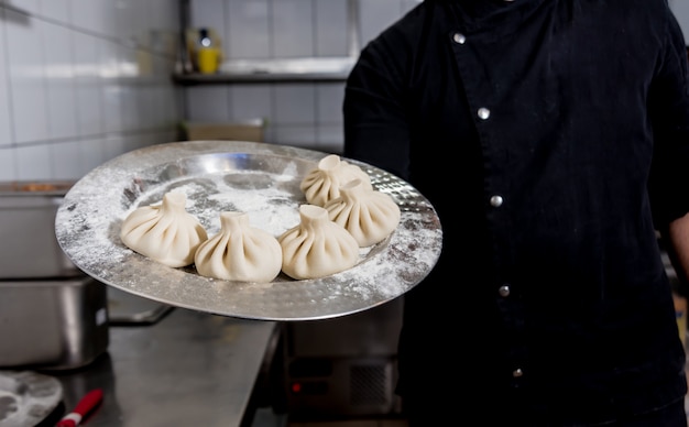 Chef-kok coocking Georgische khinkali of Japanse wonton.