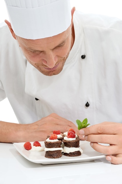 Chef-kok dessert en munt op zoet voedsel door culinaire kok met chocolade recept op een bord geïsoleerd in witte studio achtergrond Koken presentatie en man die minicakes maakt als keuken voor lekker eten