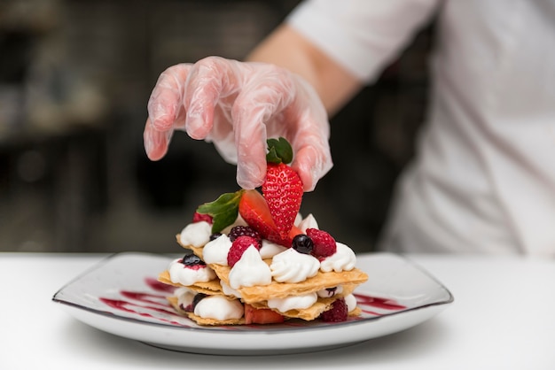 Chef-kok die aardbei op dessert zet