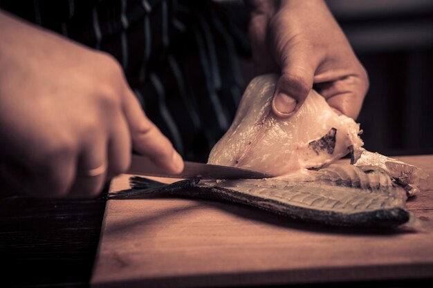 Chef-kok die de vis op een bord snijdt?