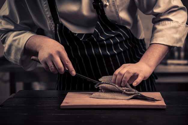 Chef-kok die de vis op een bord snijdt?