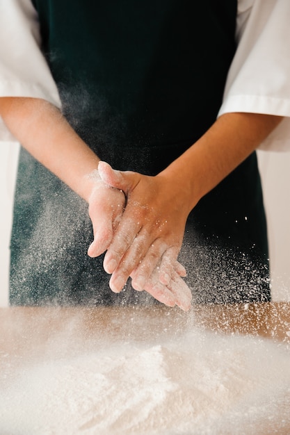 Foto chef-kok die deeg voorbereidt. kookproces, werk met bloem.