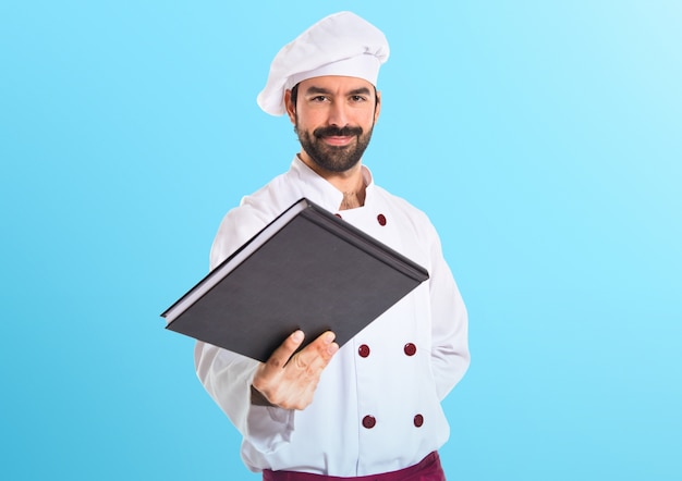 Chef-kok die een boek op kleurrijke achtergrond geeft