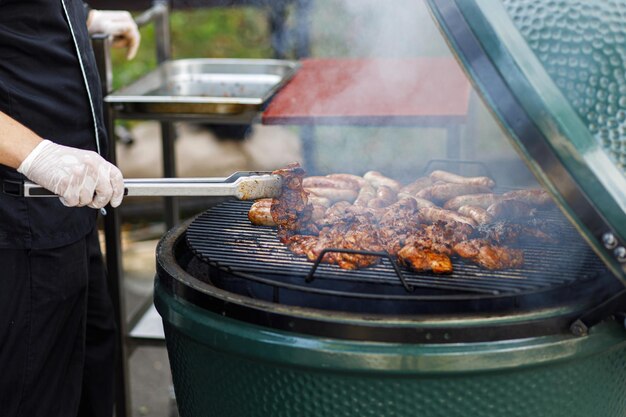 Chef-kok die heerlijk bbq-vlees kookt in de grill op de straatmarkt in de stad verkoper die biefstuk roostert op festival