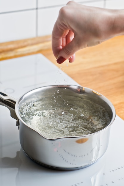 Chef-kok die het water voor het koken van rivierkreeften zoutt.