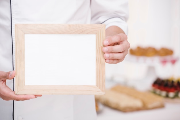 Chef-kok die houten frame met model voorstelt