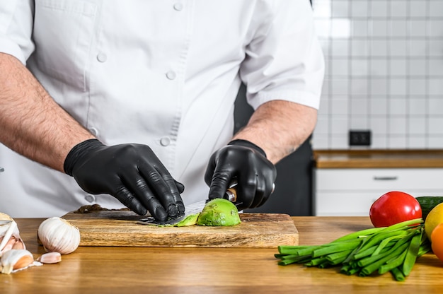 Chef-kok die in zwarte handschoenen guacamole voorbereidt
