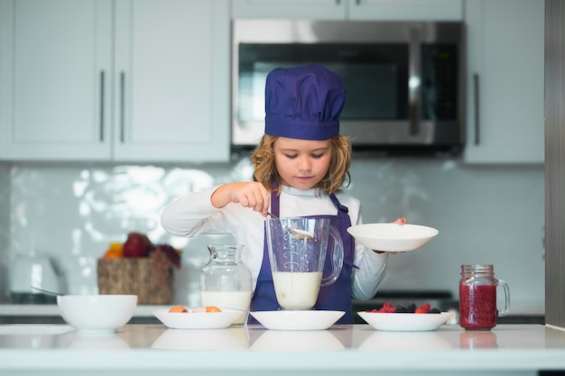 Chef-kok die lekker eten bereidt bij keukenjongen die smakelijke, heerlijke kleine jongen maakt met chef-kokhoed en een ap