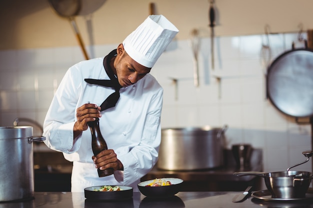 Foto chef-kok die peper op een maaltijd bestrooit