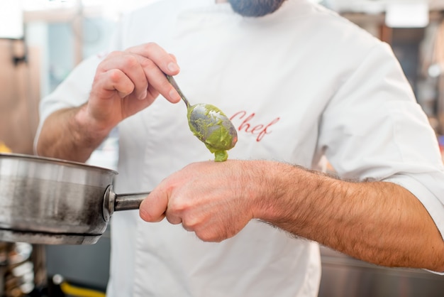 Chef-kok die saus op de hand legt om te proeven