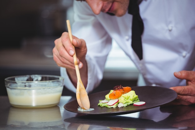 Chef-kok die saus op een schotel zet