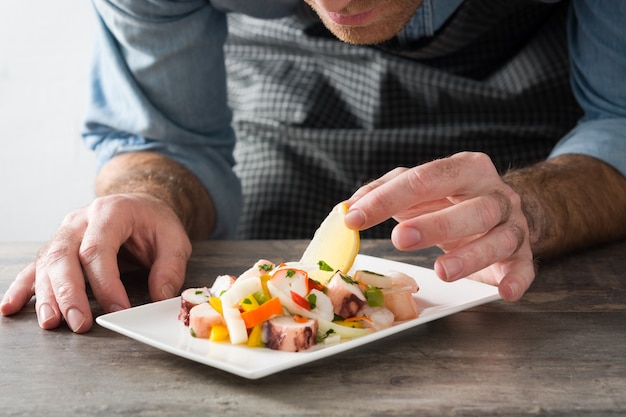 Foto chef-kok die zeevruchten ceviche op houten lijst voorbereiden