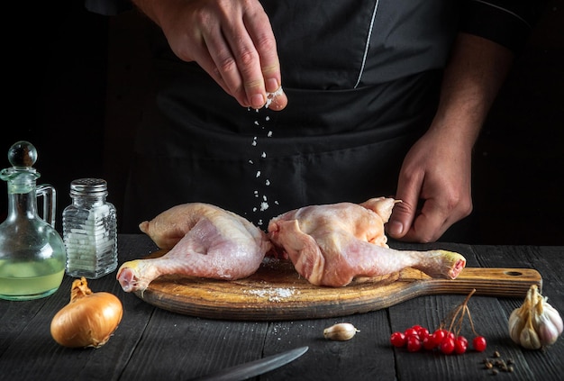 Chef-kok die zout toevoegt aan kippenpoten in de keuken