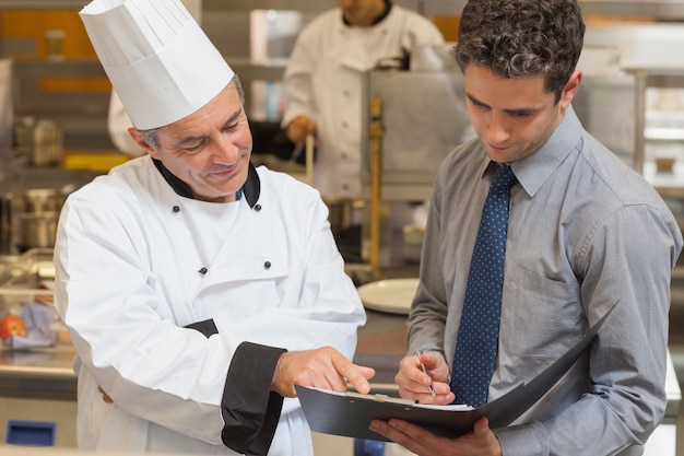 Chef-kok en ober bespreken menu in de keuken