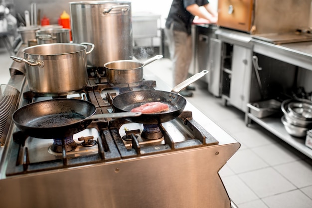 Chef-kok frituren vlees steak op het gasfornuis in de keuken