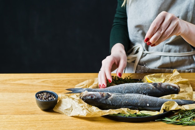 Chef-kok gezouten zeebaars op een houten tafel.