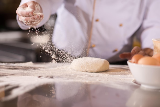 chef-kok handen bereiden deeg voor pizza op besprenkeld met bloem tafel close-up