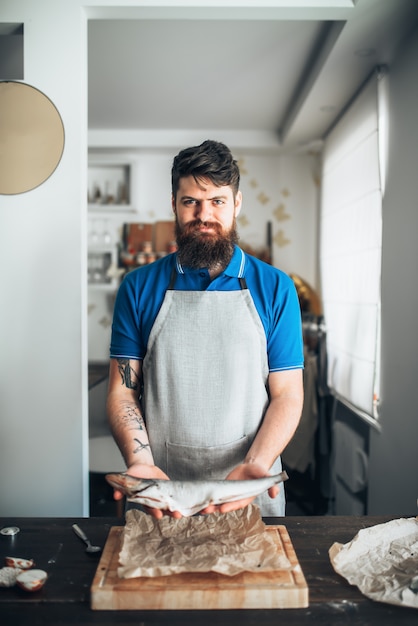 Chef-kok handen houdt rauwe vis over snijplank