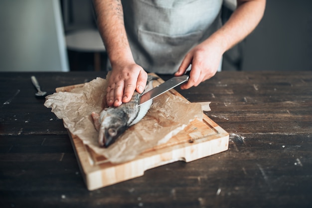 Chef-kok handen met mes gesneden vis op snijplank