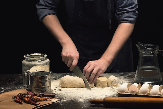 Chef-kok handen snijden pizzadeeg op houten tafel