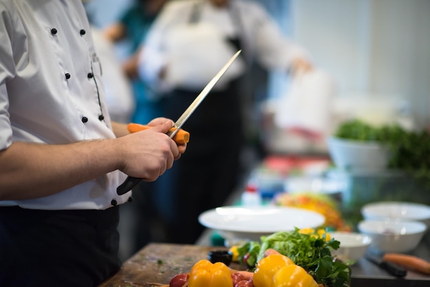 chef-kok handen snijden wortelen op een houten tafel voorbereiding voor maaltijd in restaurant