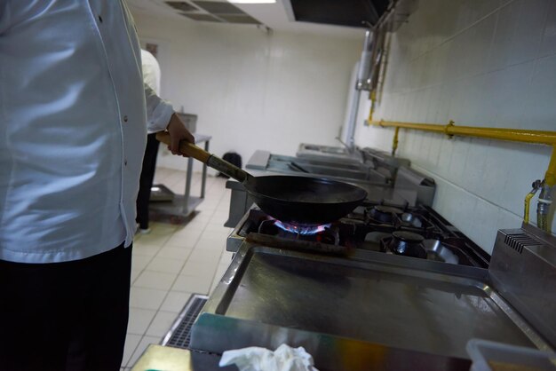 chef-kok in de keuken van het hotel bereidt plantaardig voedsel met vuur