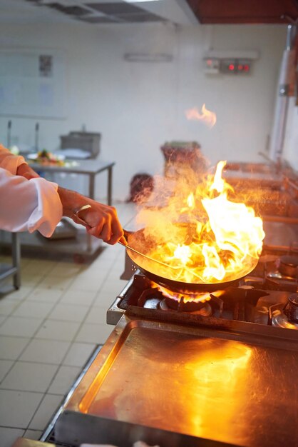 chef-kok in de keuken van het hotel bereidt plantaardig voedsel met vuur