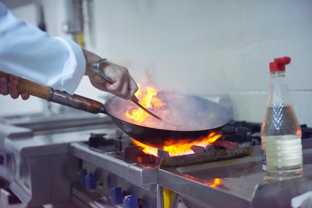 chef-kok in de keuken van het hotel bereidt plantaardig voedsel met vuur