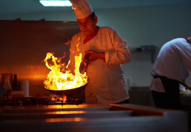 chef-kok in de keuken van het hotel bereidt plantaardig voedsel met vuur