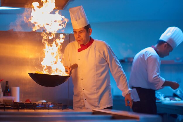 chef-kok in de keuken van het hotel bereidt plantaardig voedsel met vuur