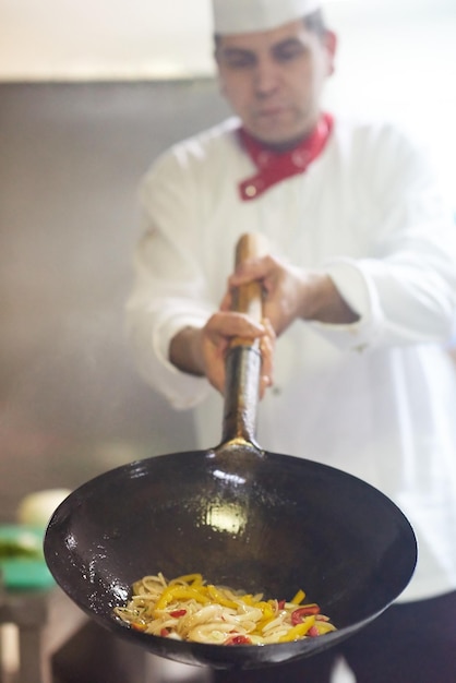 chef-kok in de keuken van het hotel bereidt plantaardig voedsel met vuur