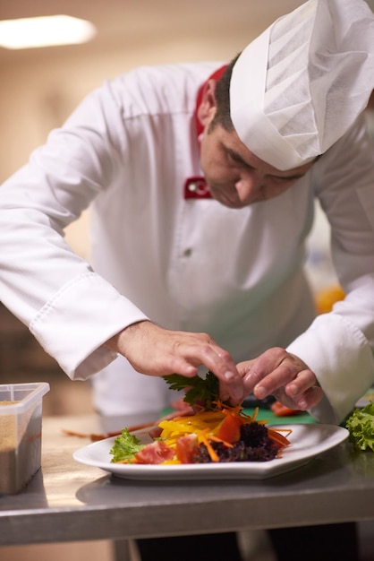 chef-kok in de keuken van het hotel die voedsel, heerlijke groenten en vleesmaaltijden bereidt en decoreert