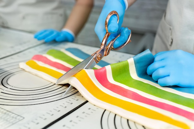 Chef-kok in handschoenen lijmt veelkleurige hete karamellolly's op een stokje Handgemaakt werk