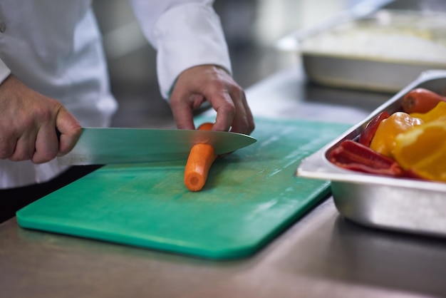 chef-kok in hotelkeuken snijdt groenten met mes en bereidt voedsel voor