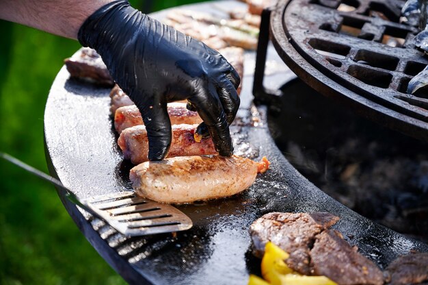 Chef-kok in rubberen handschoenen frietjes worstjes op de grill