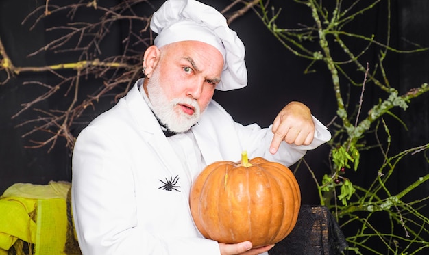 Chef-kok in uniform met pompoen happy halloween dieet voedsel gezonde biologische oogst groenten