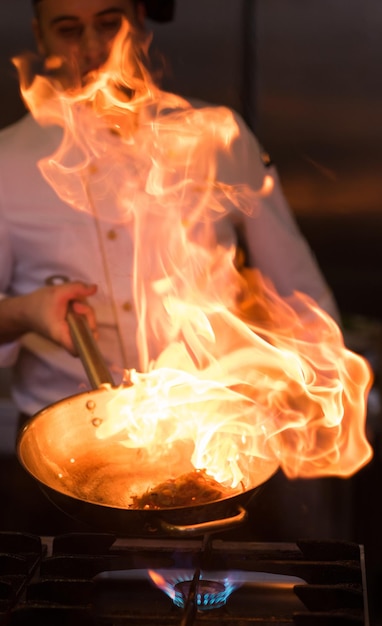 Chef-kok koken en flamberen op eten in de keuken van het restaurant