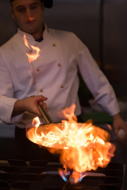 Chef-kok koken en flamberen op eten in de keuken van het restaurant