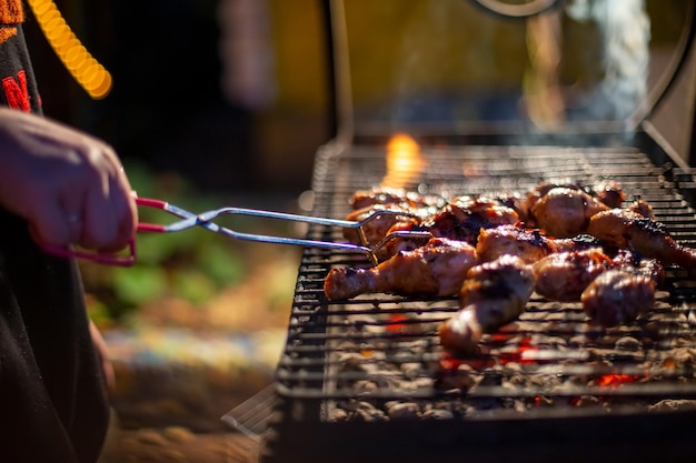 Chef-kok koken jerk barbecue bbq kip op de grill hand draaien van voedsel