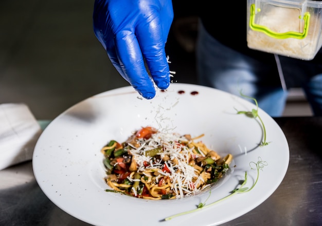 Foto chef-kok koken pasta met groenten in de pan. italiaanse keuken. restaurant.