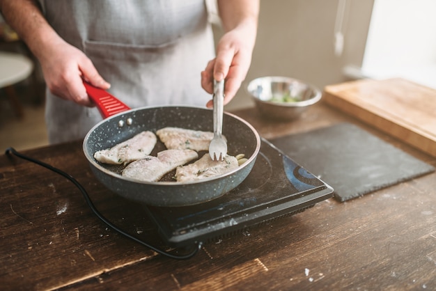 Chef-kok koken zeebaars visfilet op een koekenpan