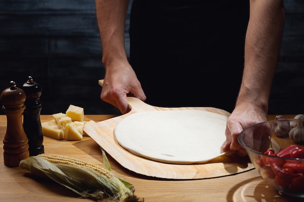 Chef-kok kookt pizza, lege pizzabodem aan boord