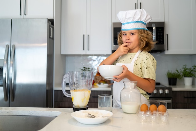 Chef-kok kookt thuis bakken in de keuken Kid chef-kok kookt koken in de keuken Koken culinair en kinderen Kleine jongen in koksmuts en schort