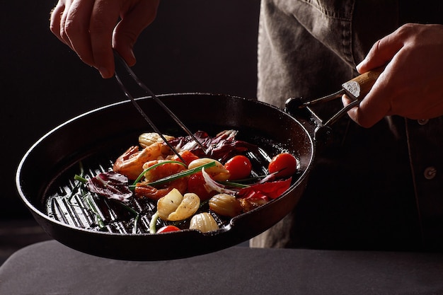 Foto chef-kok kookt zeevruchten, garnalen in een pan met groenten